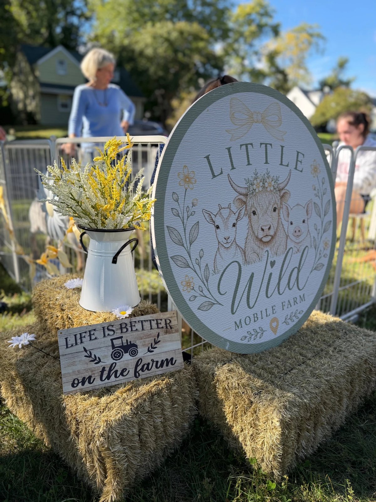 The Little Wild Mobile Farm welcome sign styled with hay bales and flowers at an event